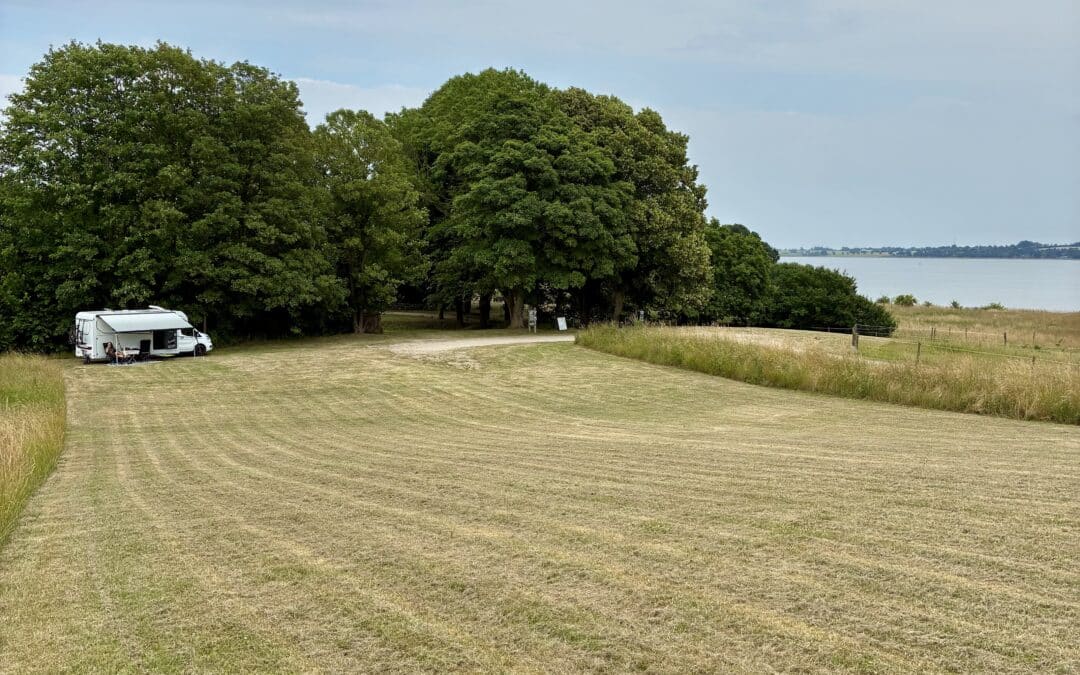 autocamper med stubmark foran og havet bag